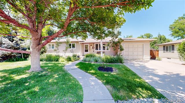 Single-story home with an attached garage, curved front walkway, and large leafy tree.