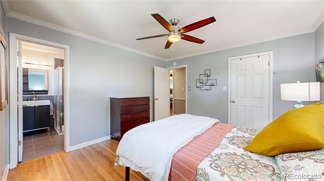 Bedroom with floral bedding, a mustard-yellow pillow, hardwood floors, and an adjoining bathroom.