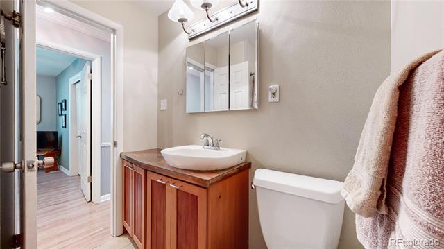 Bathroom with a wood vanity and vessel sink, mirrored cabinet, toilet, and towels.