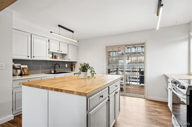 Bright kitchen with white cabinets, a butcher-block island, and sliding glass doors to a balcony.