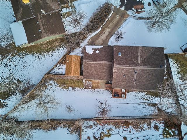 Aerial view of a house with a fenced, snow-covered yard and attached deck.
