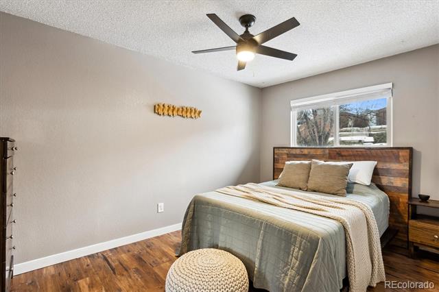 Bedroom with a wood headboard, hardwood floors, and a ceiling fan.
