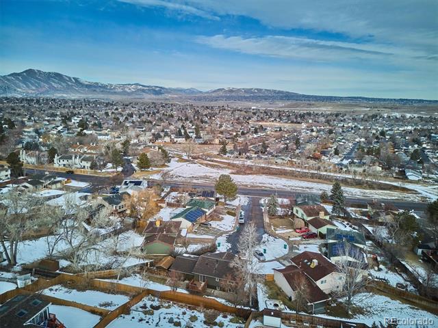 Aerial view of a snow-dusted neighborhood with the Rocky Mountain foothills in the distance.