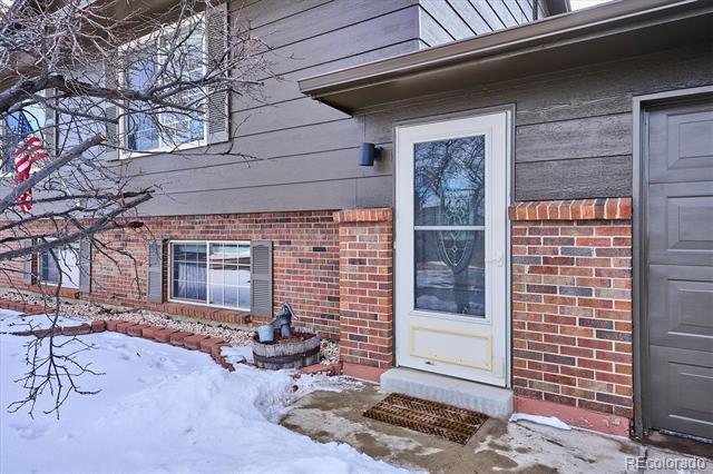 Home entrance with a white door, brick facade, and snow-covered front yard.