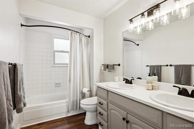 Bathroom with a double-sink vanity, bathtub-shower, and gray towels.
