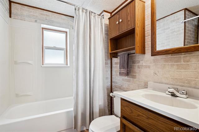 Bathroom with a white tub, window, and wood cabinetry around the sink.