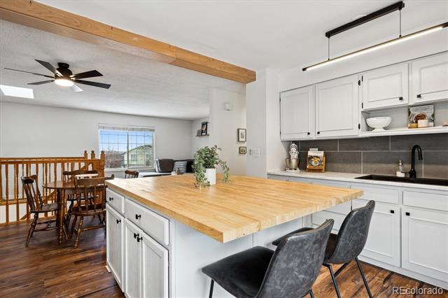 Open-plan kitchen with a large butcher-block island, white cabinets, and hardwood floors.