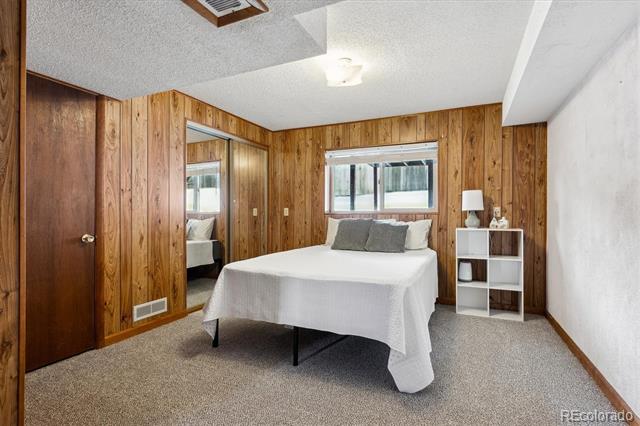 Bedroom with wood-paneled walls, a white bed, and a mirrored closet door.