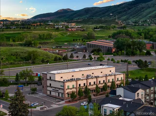 Multi-story residential building with mountain foothills behind it.