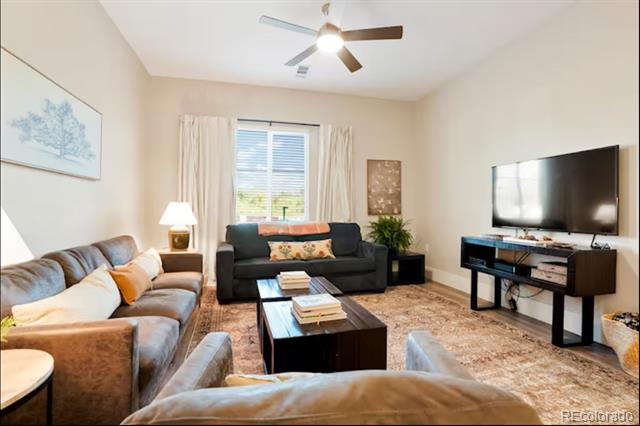 Furnished living room with a sectional, window-side loveseat, television, and ceiling fan.