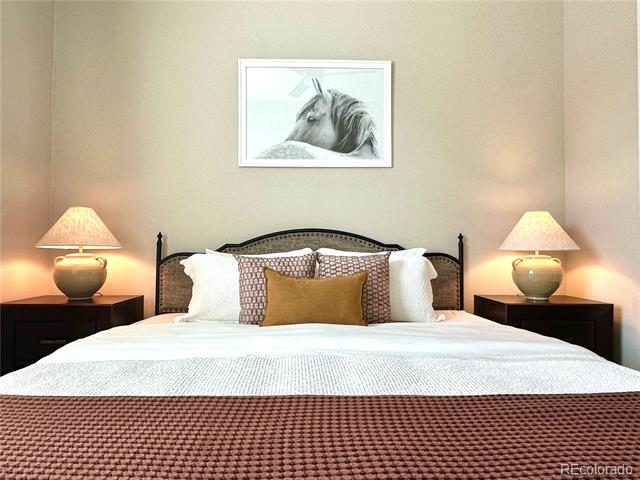 Bedroom with a large bed, matching bedside lamps, and framed horse artwork above the headboard.