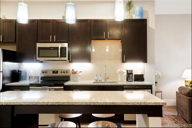 Kitchen with dark wood cabinets, stainless steel appliances, and a stone island with seating.