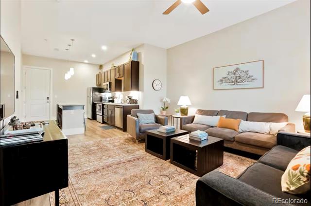 Condo living room with gray sectional sofas, dark coffee tables, and an open kitchen.