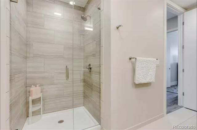 Bathroom with a glass-enclosed, gray-tiled walk-in shower and towel rack.