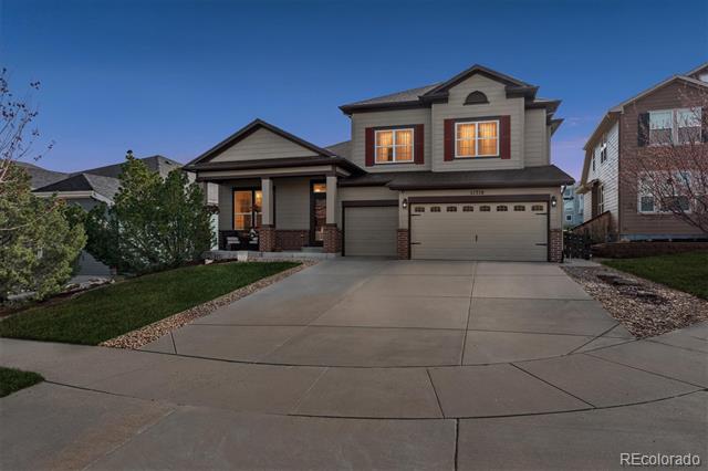 Two-story gray house with a two-car garage, brick accents, and a wide curved driveway at dusk.