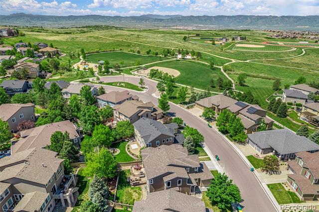 Aerial view of homes along curving streets, with green open space and mountains beyond.