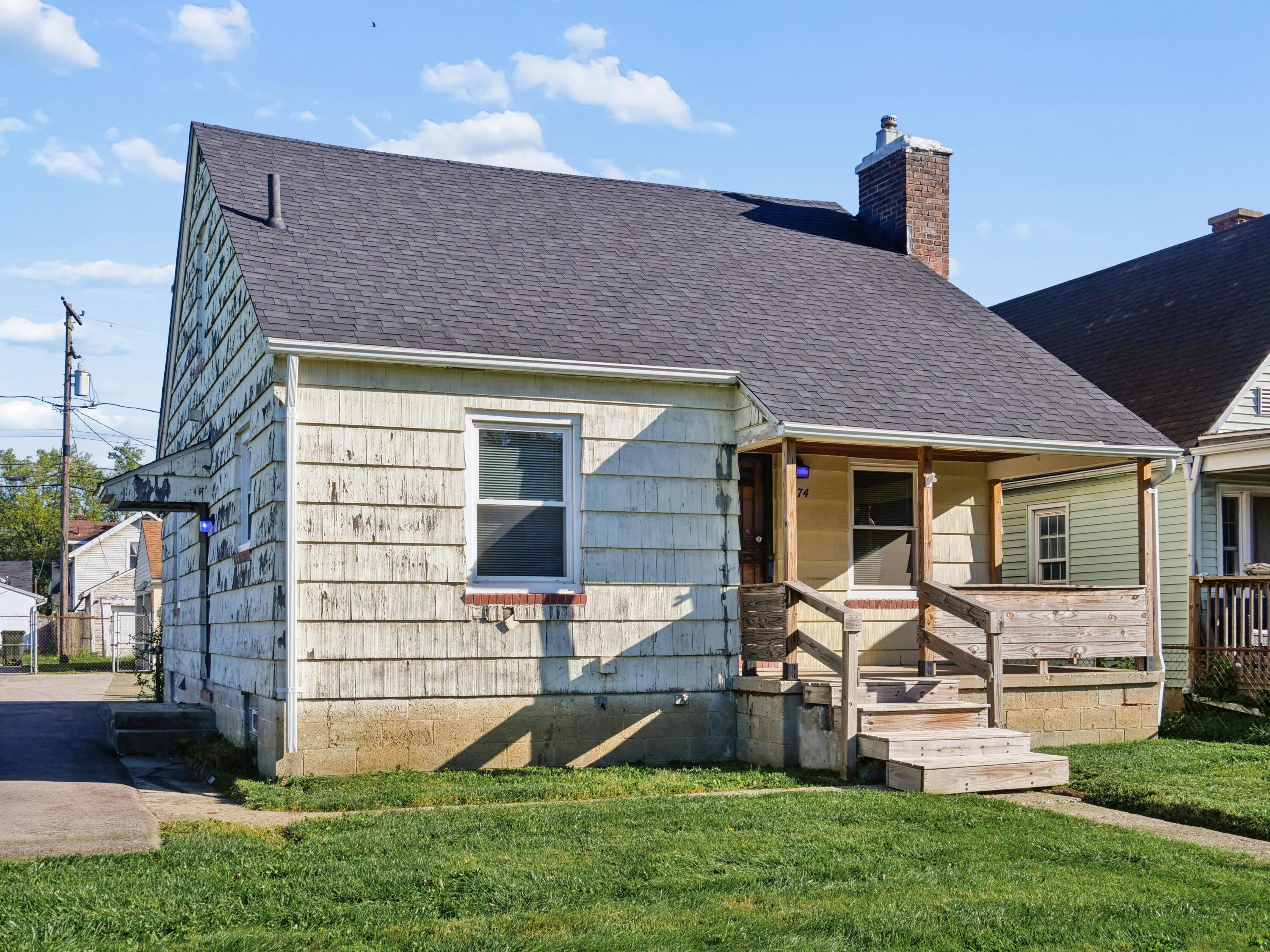 Weathered pale-sided house with a steep roof and raised wooden front porch.