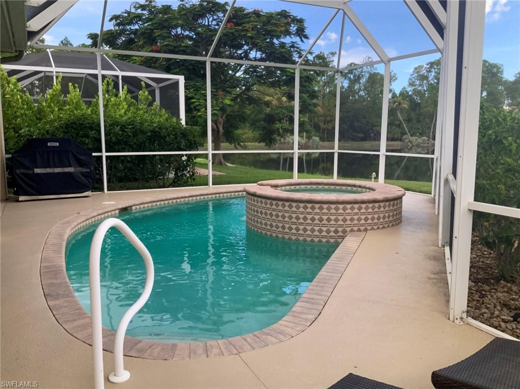 Screened pool and raised patterned spa, with a water view beyond the enclosure.