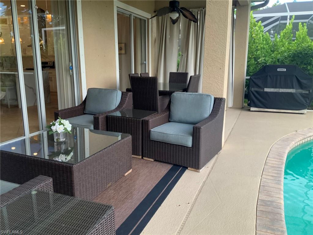 Covered patio with wicker seating beside a swimming pool and sliding glass doors.