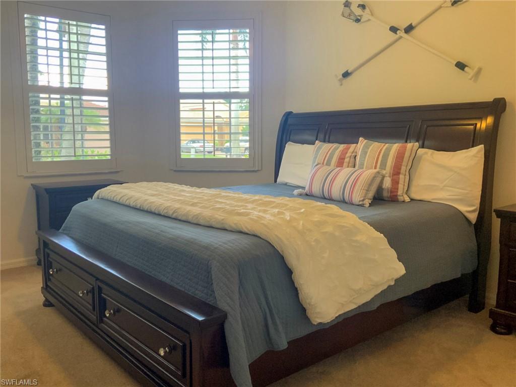 Bedroom with a dark wood bed, blue bedding, striped pillows, and two shuttered windows.