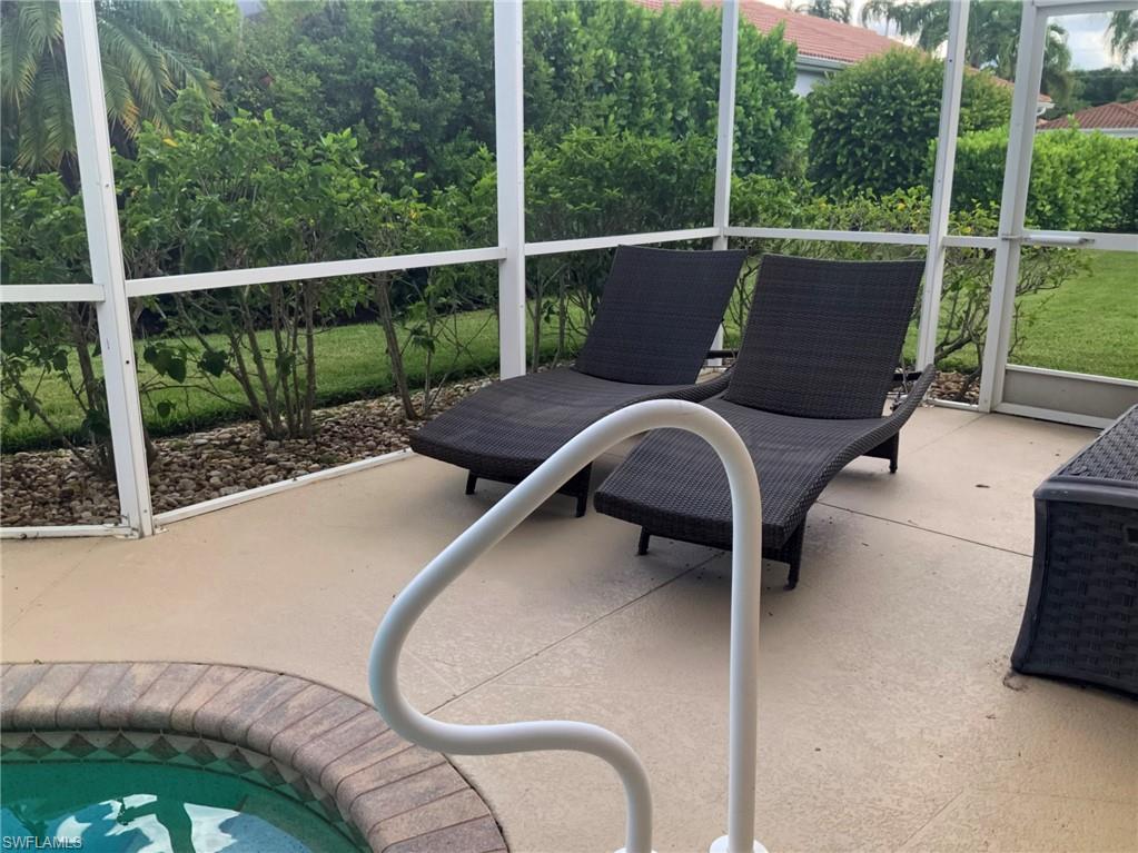 Screened pool patio with two woven chaise lounges and a white handrail.