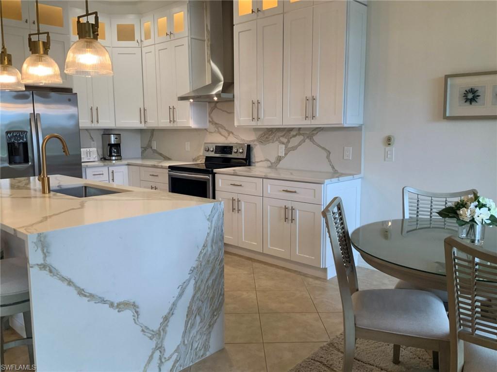 Kitchen with white cabinets, marble-patterned counters, and a large waterfall island.