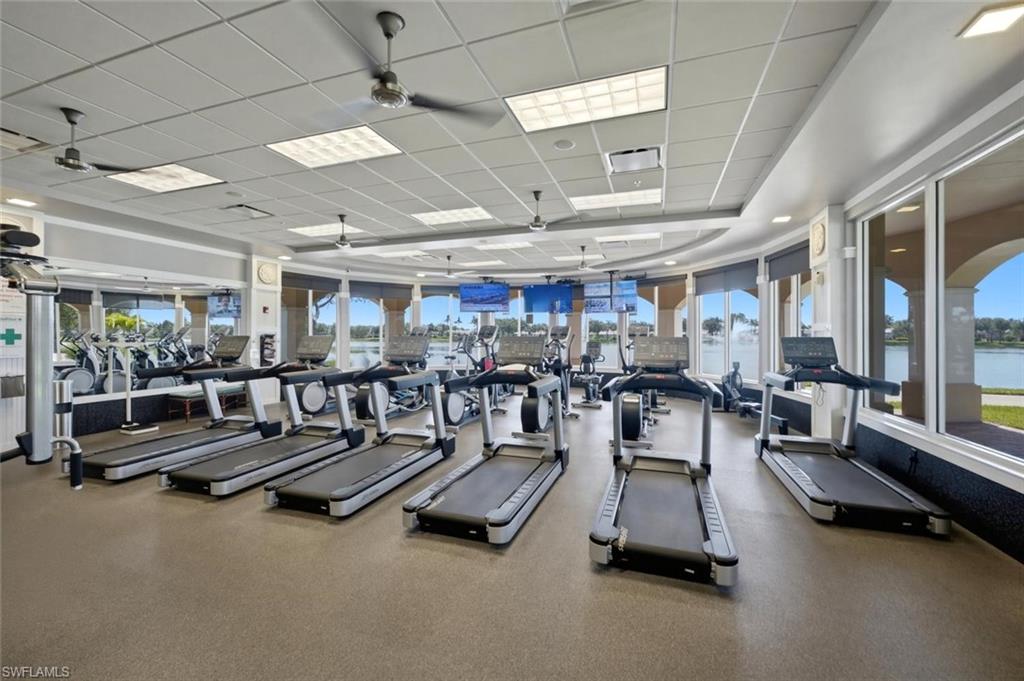 Fitness room with rows of treadmills and exercise bikes beside windows overlooking the water.
