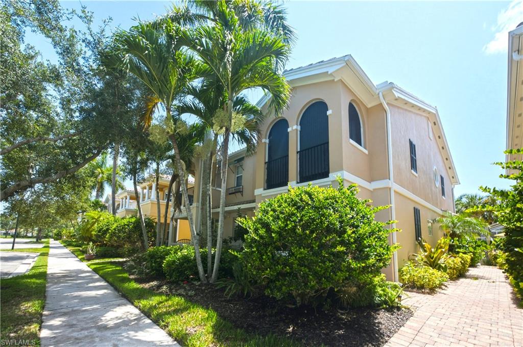 Two-story peach stucco home with arched windows, palm trees, and landscaped grounds.