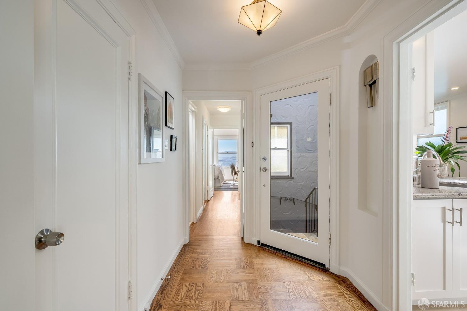 Entry hall with hardwood floors, a glass-paneled front door, and a distant water view.