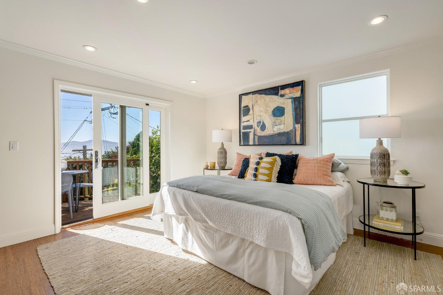 Staged bedroom with a neatly made bed and sliding glass doors opening to a small deck.