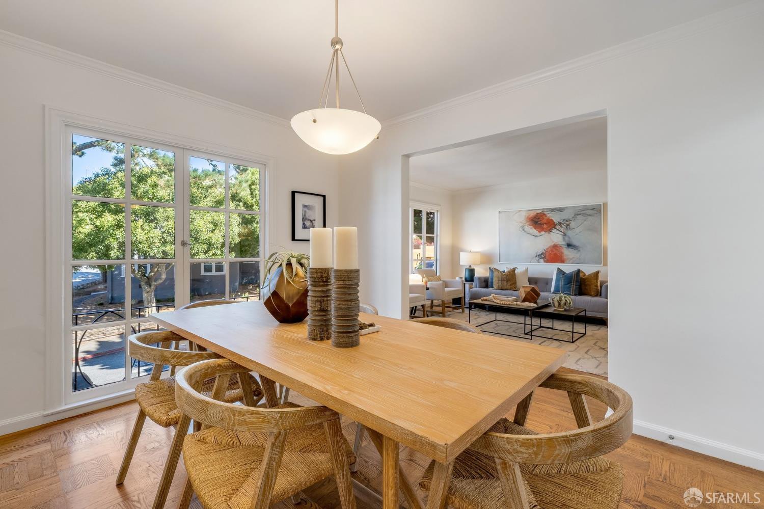 Dining room with a light wood table, woven chairs, and an adjoining living room.
