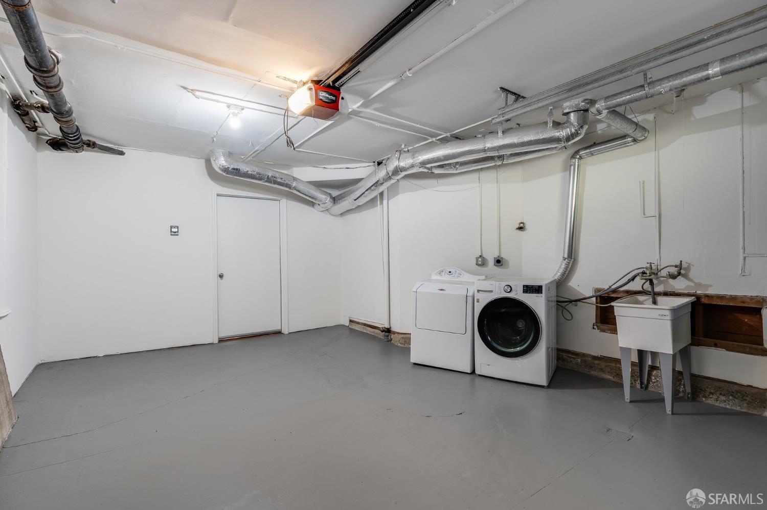 Utility room with washer and dryer, exposed ceiling ducts, and a sink.