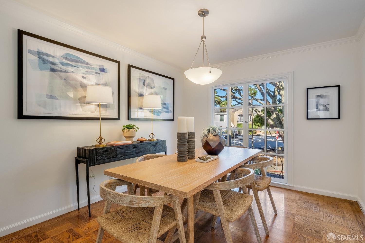 Dining room with a light-wood table, woven chairs, and a large street-facing window.