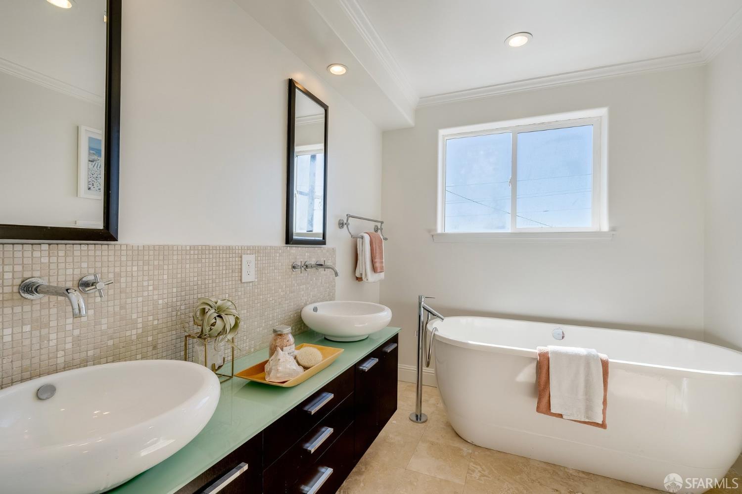 Bathroom with a freestanding soaking tub and a vessel sink on a green glass vanity.