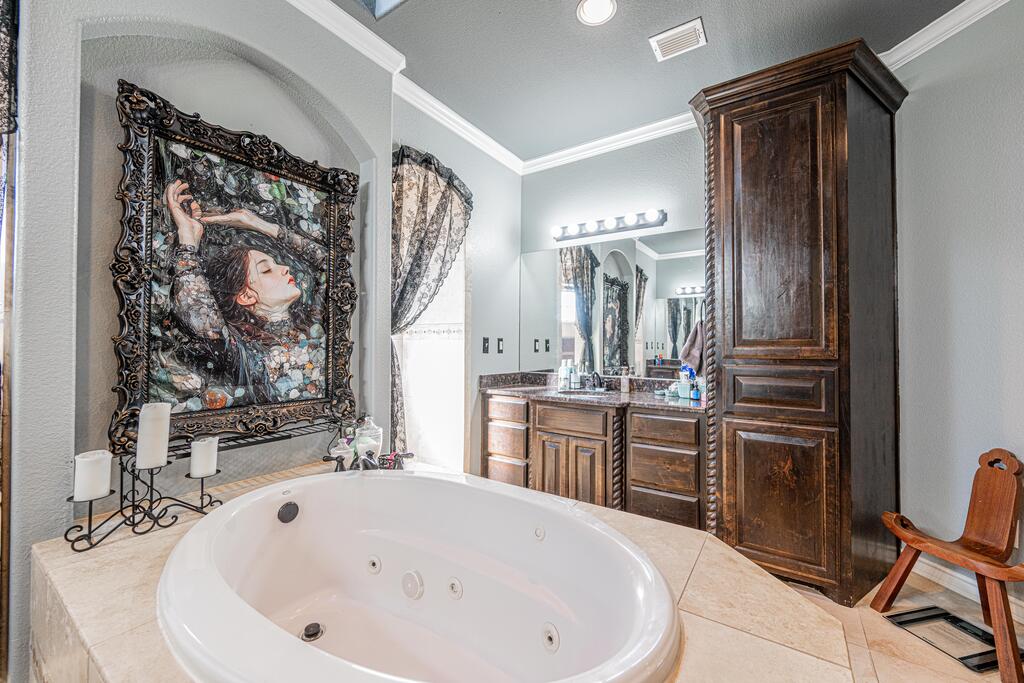 Bathroom with a large jetted tub, dark wood vanity, and ornate framed artwork.