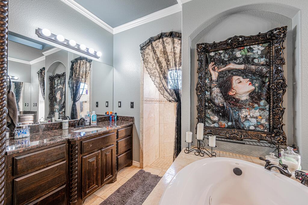 Bathroom with a white soaking tub, dark wood vanity, and ornate framed artwork.