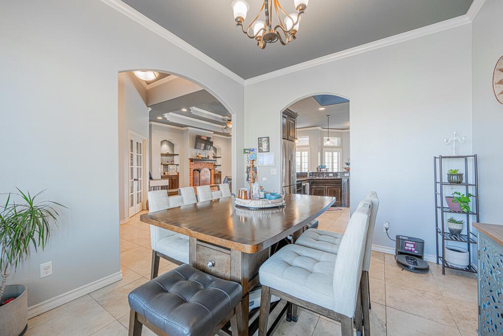 Dining room with a large wood table, upholstered chairs, and arched openings to adjoining rooms.
