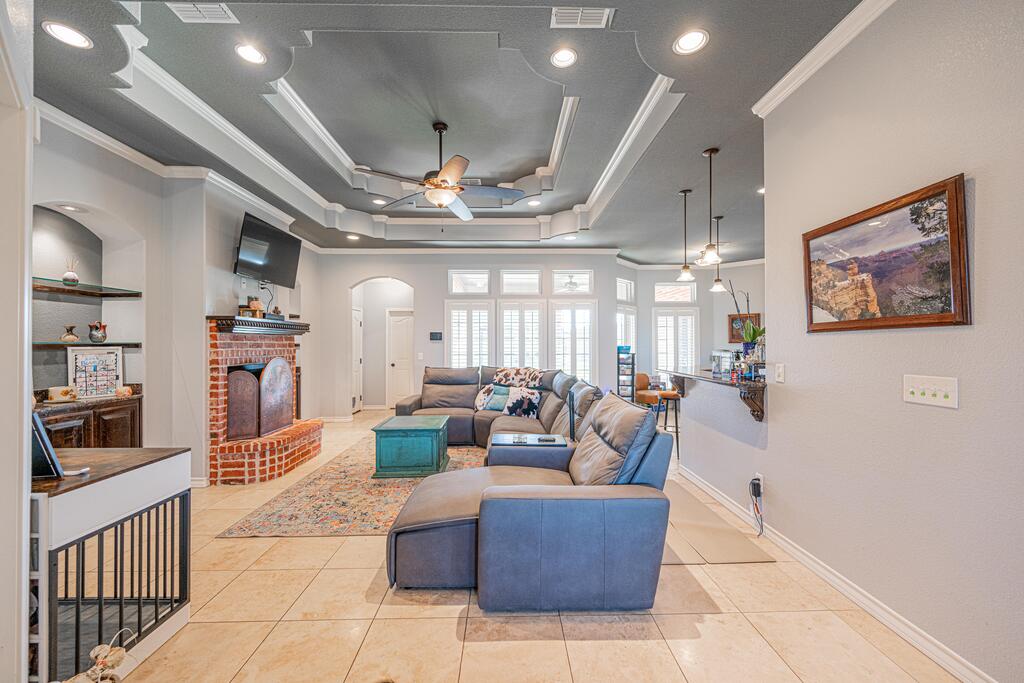 Living room with a gray sectional, brick fireplace, built-in shelves, and tray ceiling.
