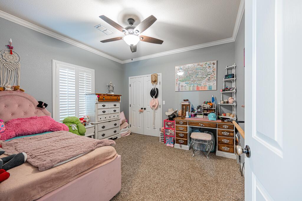 Bedroom with a pink upholstered bed, white shutters, and a desk beneath a wall map.