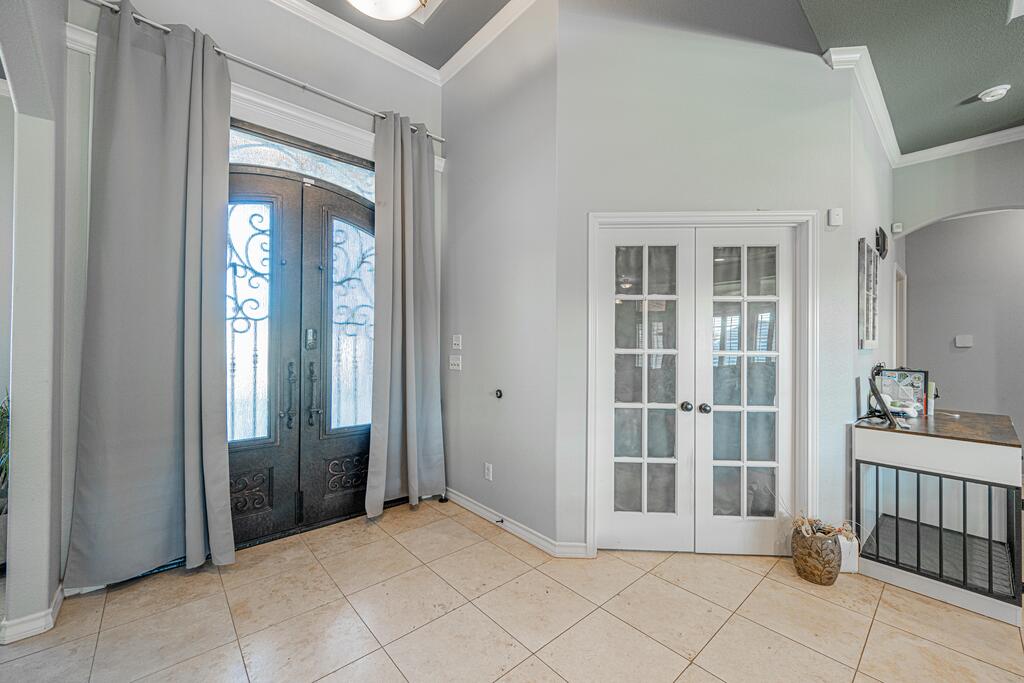 Entry foyer with an ornate dark double front door and white glass-paneled French doors.