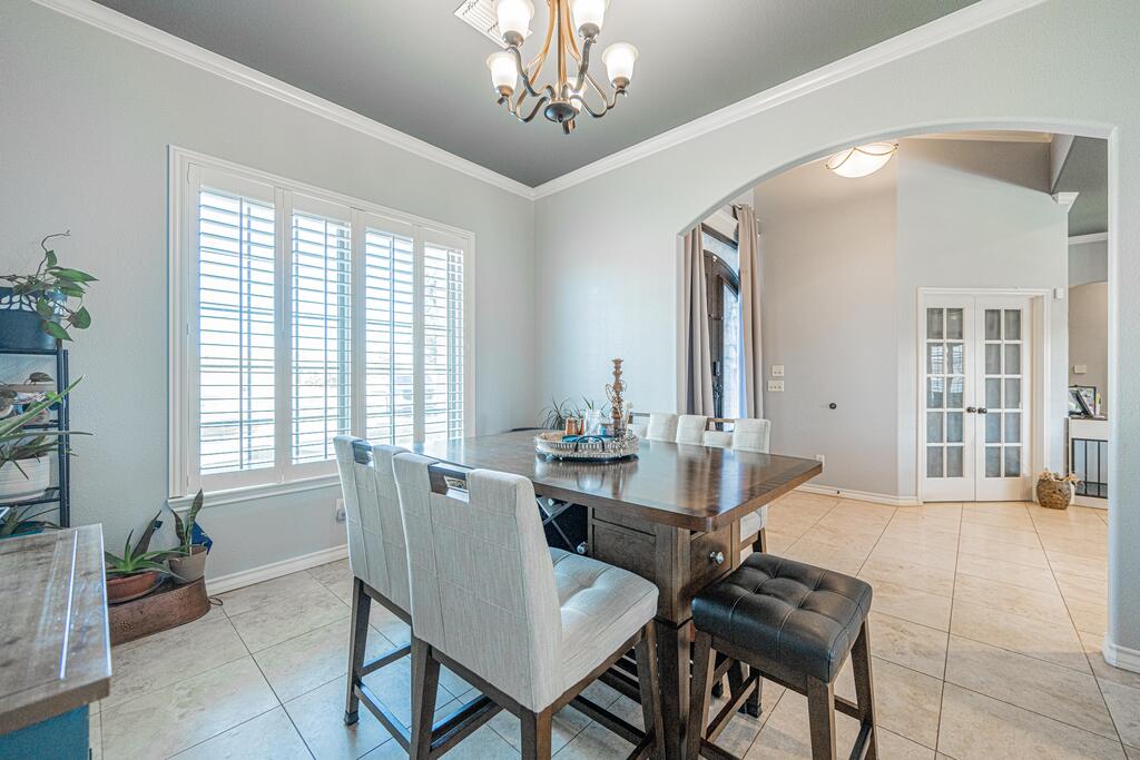 Dining room with a dark wood table, upholstered chairs, and plantation shutters.
