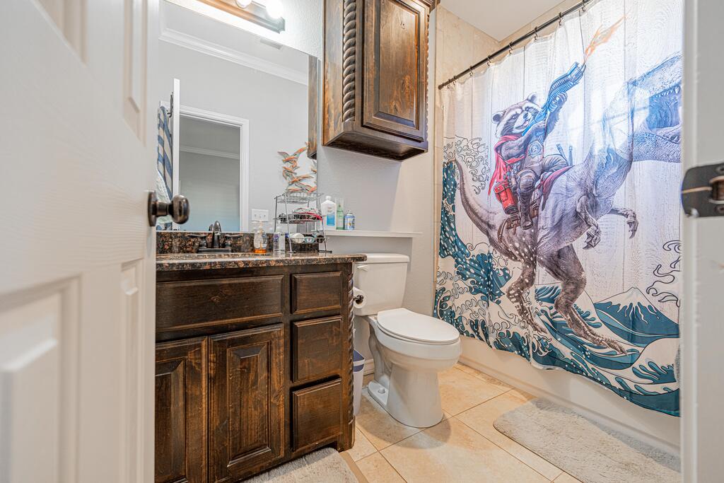 Bathroom with a dark wood vanity, granite countertop, and colorful western-themed shower curtain.