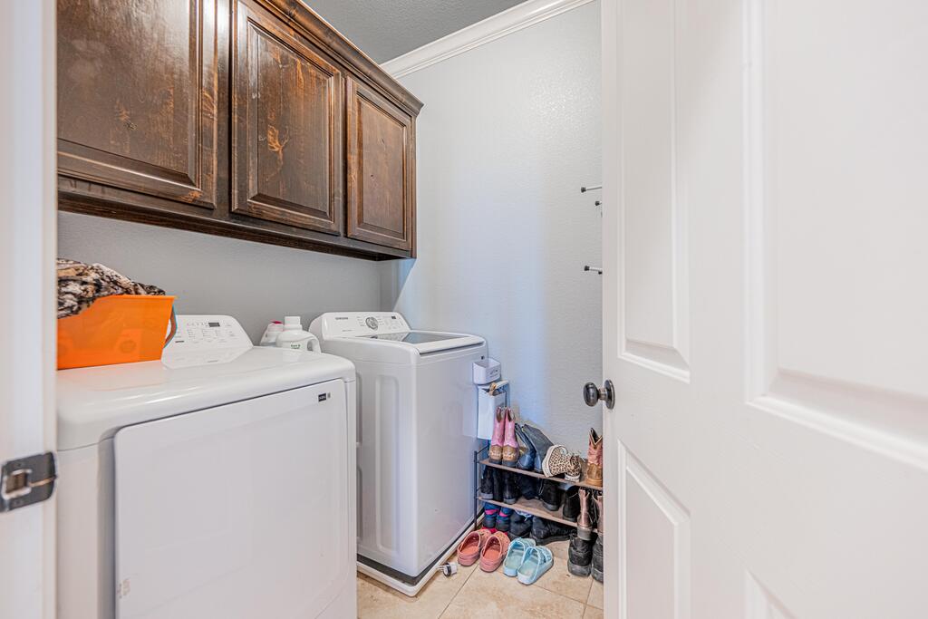Laundry room with washer and dryer beneath dark wood cabinets and a shoe rack.