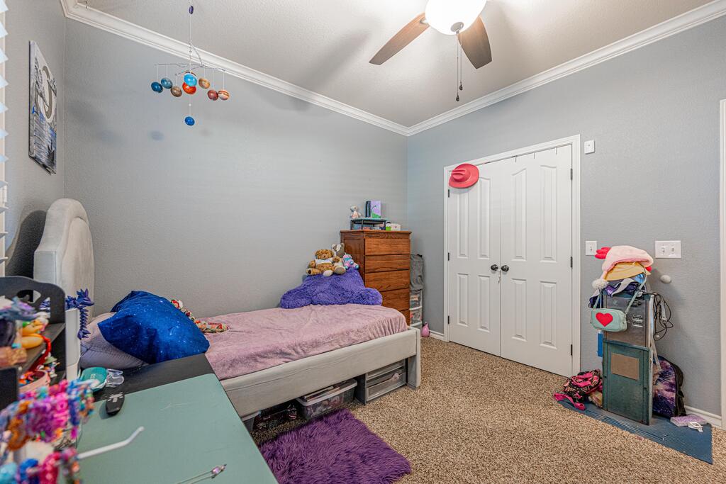 Bedroom with pink bedding, blue pillows, and white double closet doors.