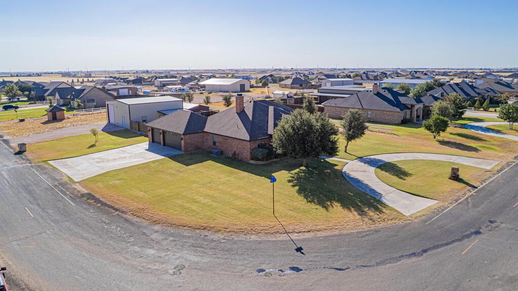 Aerial view of a brick home with a detached metal workshop on a corner lot.