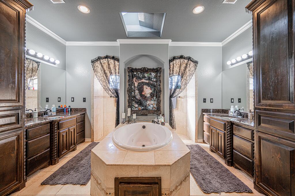 Bathroom with a central jetted tub, dark wood vanities, and stone countertops.