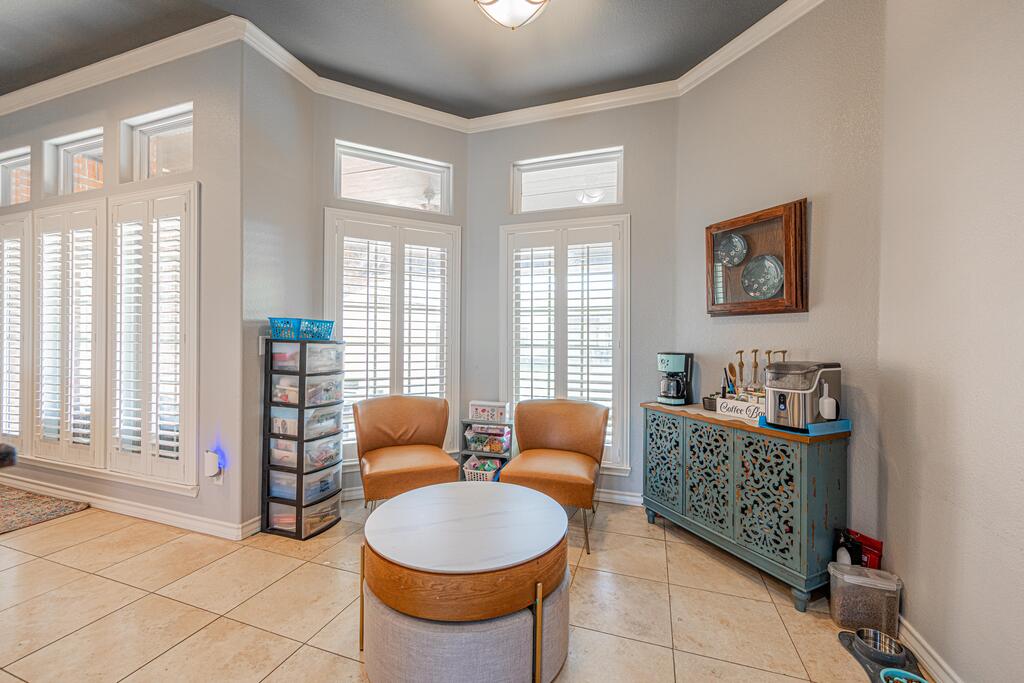 Sitting area with brown armchairs, a round coffee table, shuttered windows, and a turquoise coffee bar.
