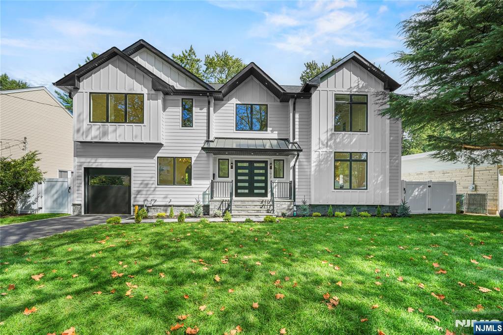 Two-story white home with dark gables, a double garage, and a broad green front lawn.