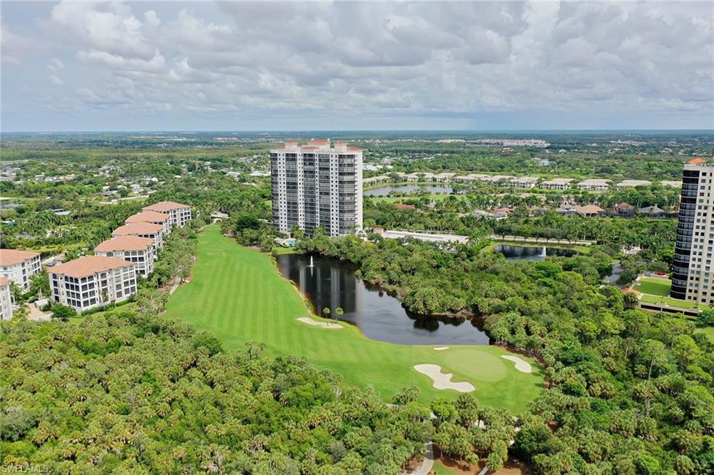 Aerial view of a golf course community with a pond, sand traps, and residential towers.