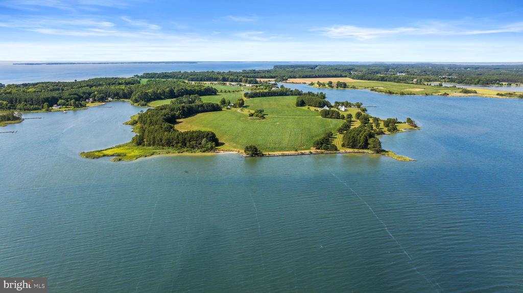 Aerial view of green waterfront land extending into a broad blue bay.